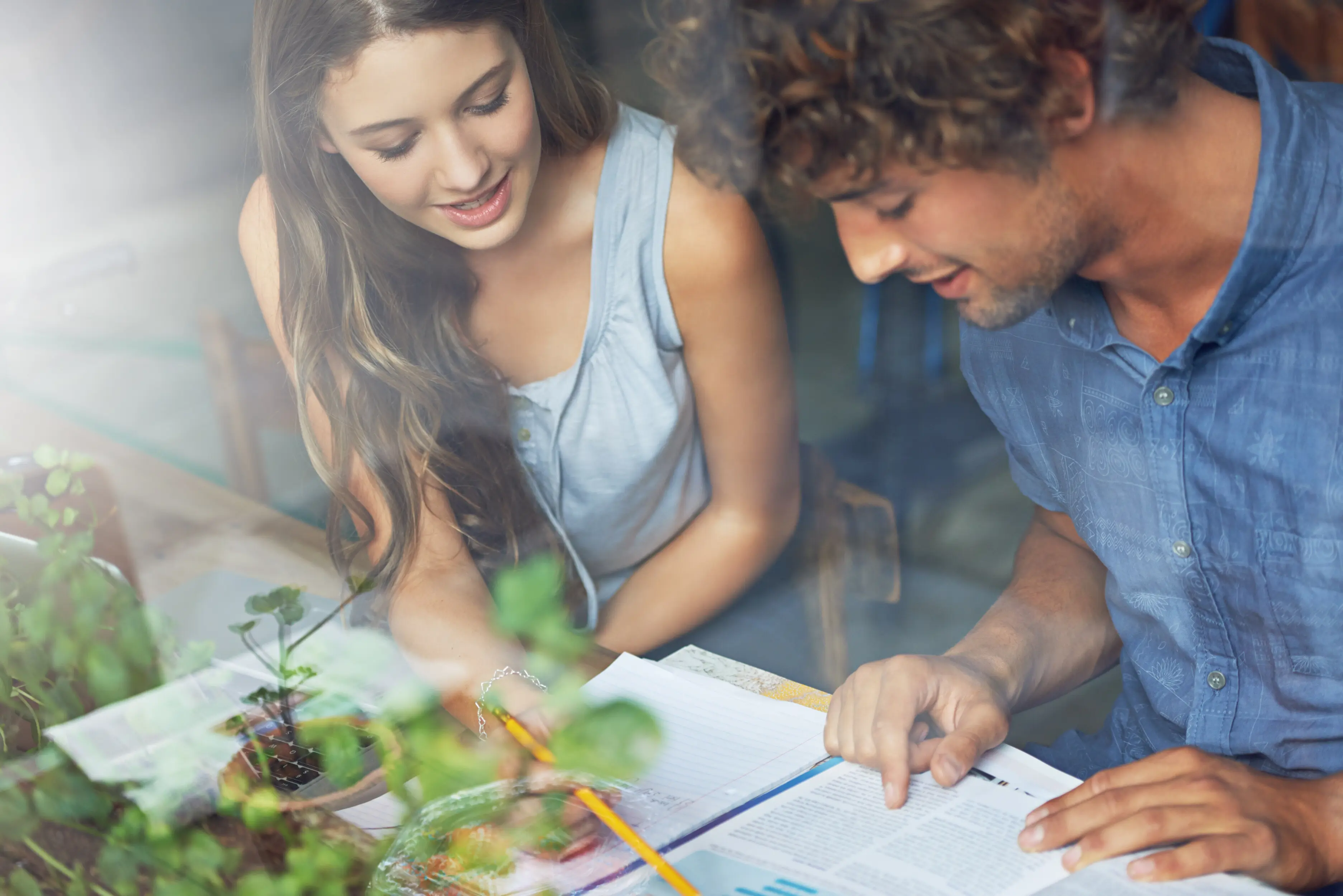 Man and woman, a couple, communicate and study by a café window and indoors at a student center, researching with a book; conversation for a journalism exam or test, thinking on date, people, and reading.